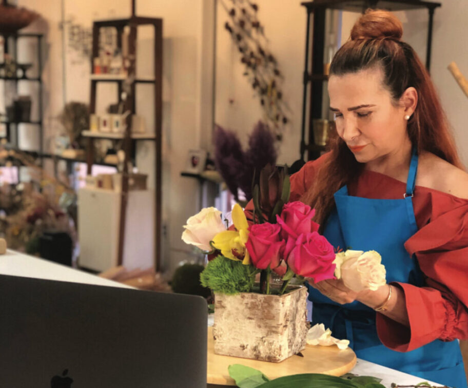 woman in front of a laptop while arranging flowers